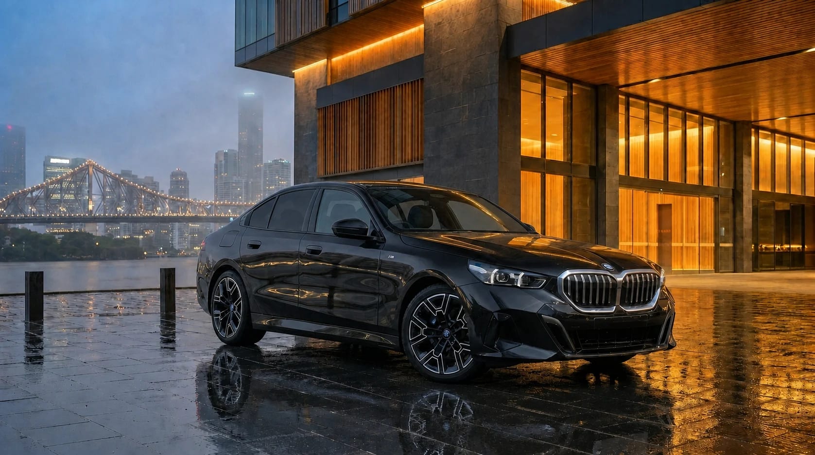 A black BMW 5 Series beside the Brisbane River and Story Bridge at dusk.
