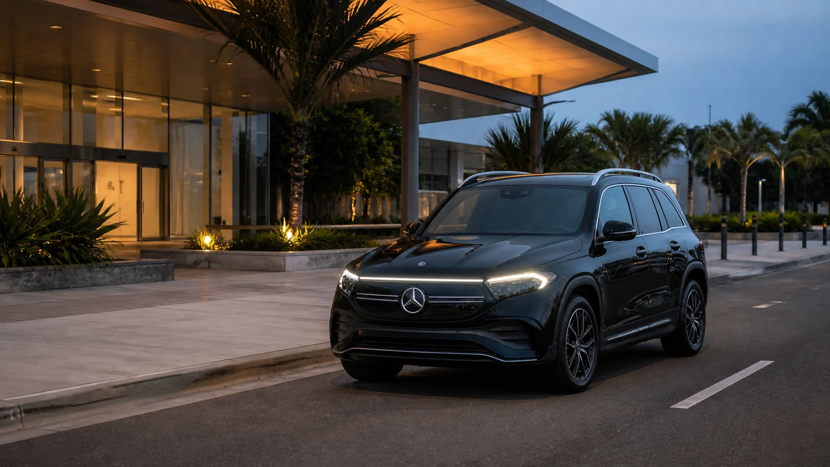A black Mercedes-Benz EQB outside a modern airport terminal at blue hour.