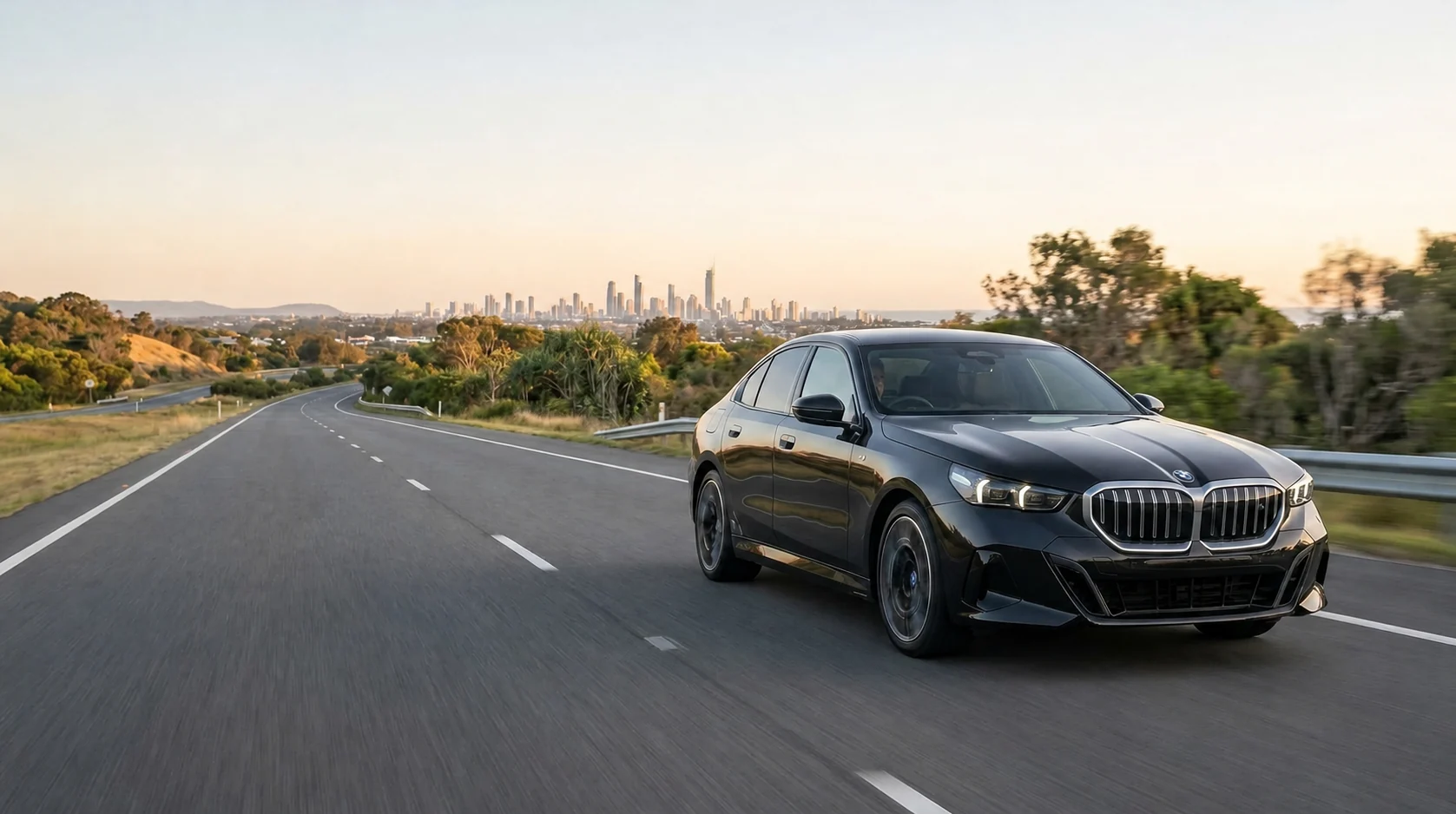 A BMW 5 Series on an open road at sunset, without a visible registration plate.