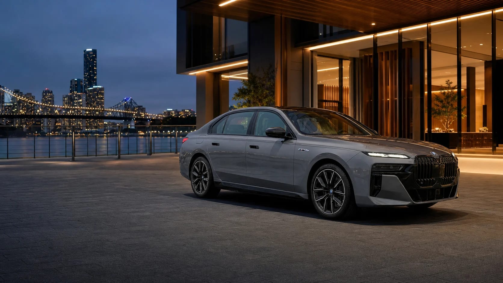 A grey BMW 7 Series waiting outside a warmly lit Brisbane riverside venue.