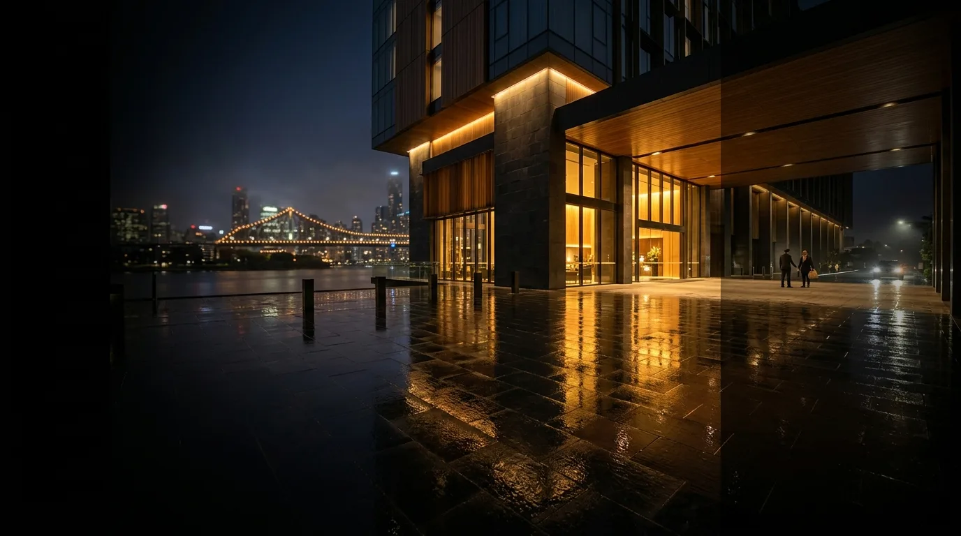 A warmly lit luxury riverside building in Brisbane at night.
